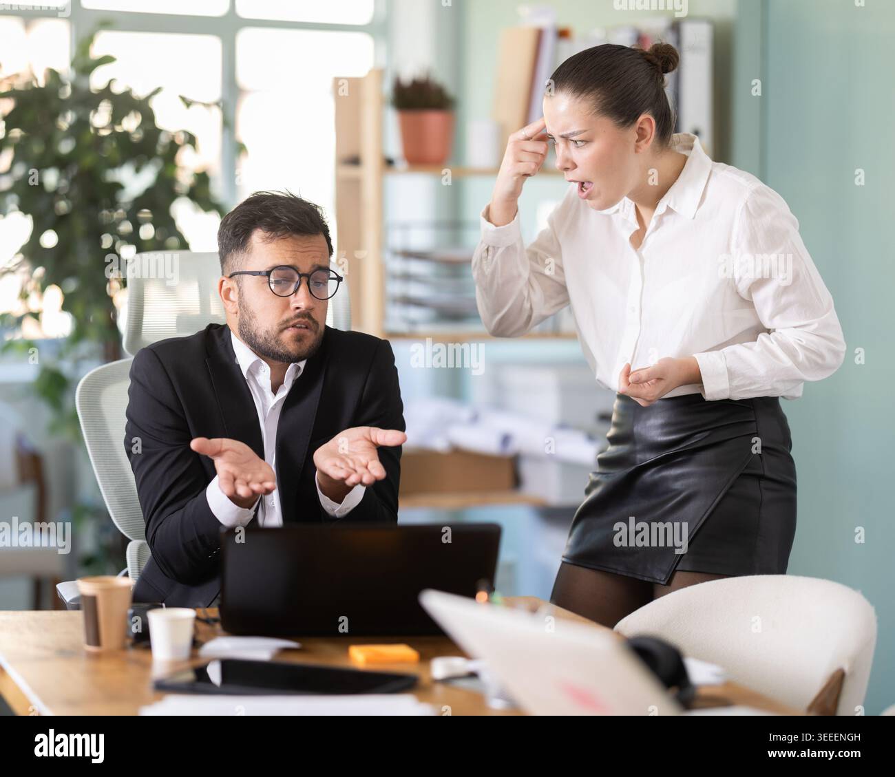 female boss stands in the office and scolds on a male IT department employee Stock Photo