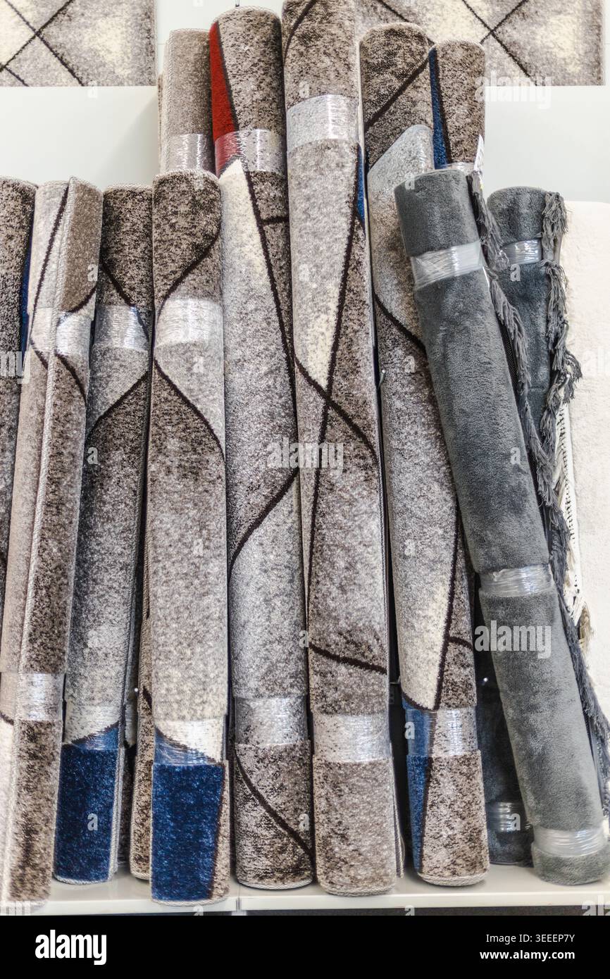 Rolled decorative carpets and modern rugs displayed in home improvement store Stock Photo