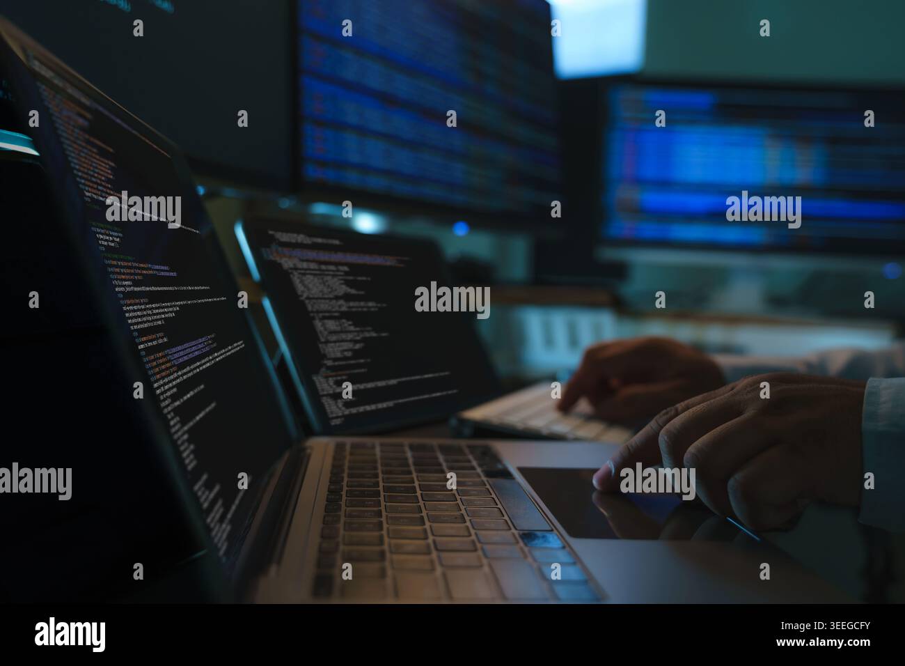 Developers coding a new application project at a multi screen workstation with laptop and digital devices, showing software development workflow, prog Stock Photo
