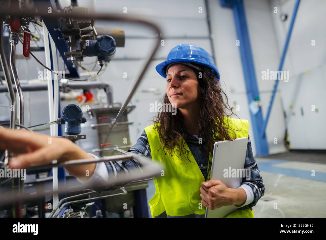 Female worker checking industrial control systems in production environment. Stock Photo