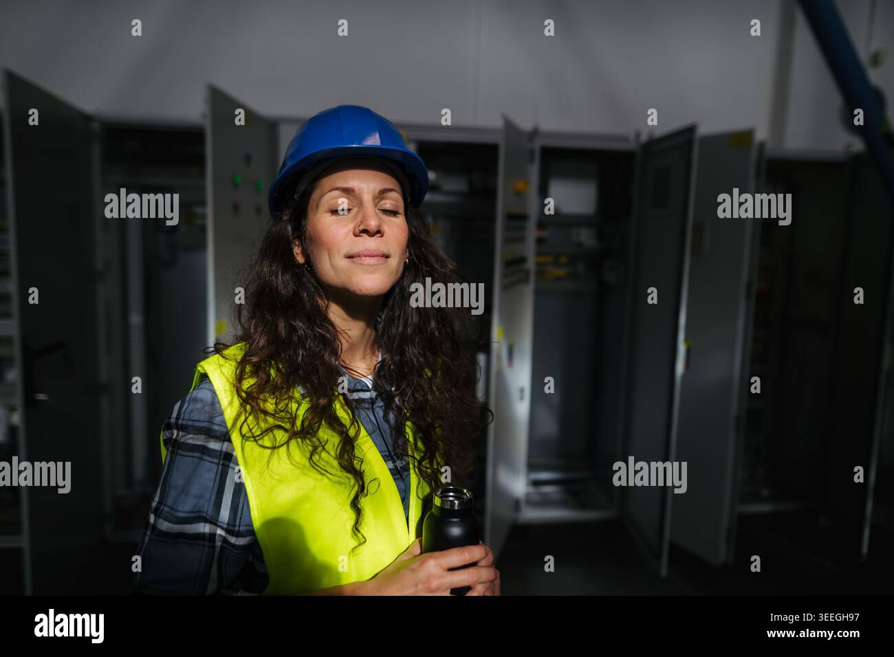 Female worker checking industrial control systems in production environment. Stock Photo