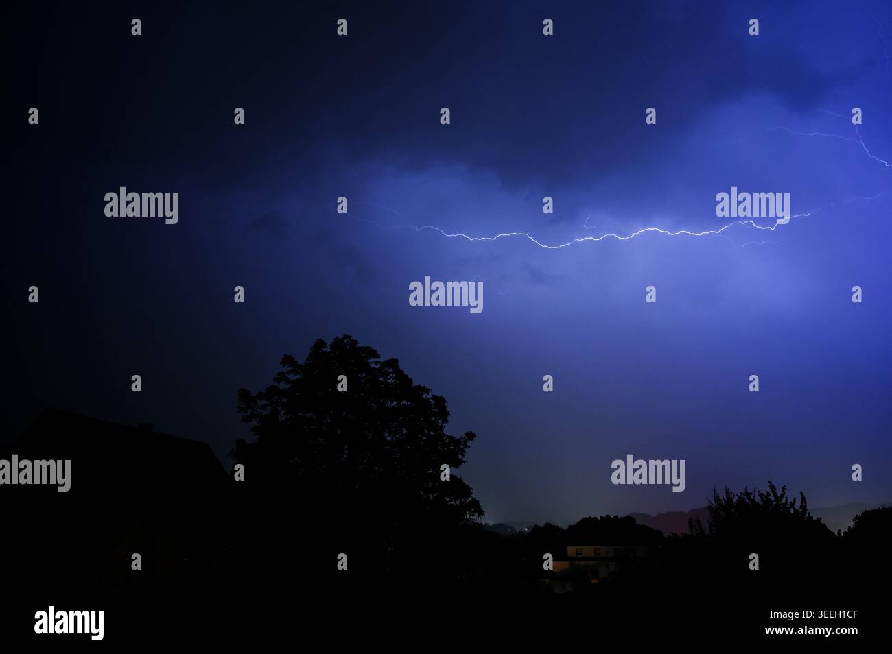 Dramatic lightning strike illuminates the night sky over silhouetted ...
