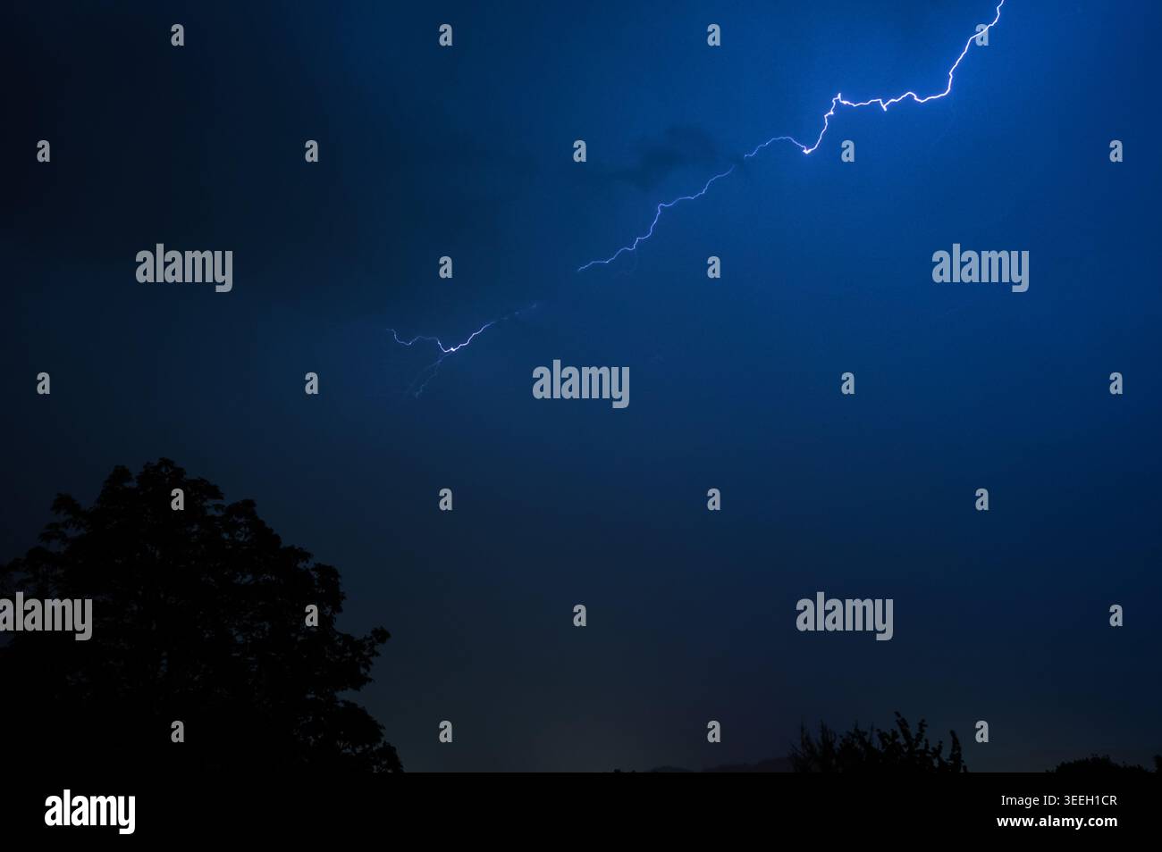 Dramatic lightning bolt illuminating a stormy night sky with dark ...