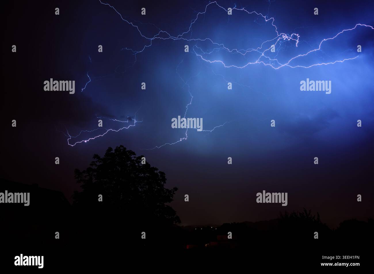 Dramatic lightning strikes illuminate the night sky over silhouetted ...