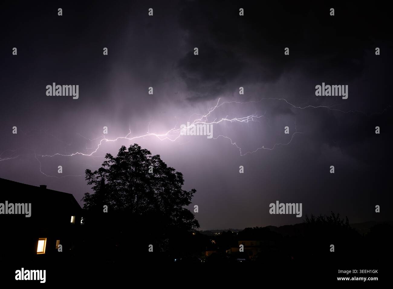 Dramatic lightning strike illuminates the night sky over a silhouetted ...