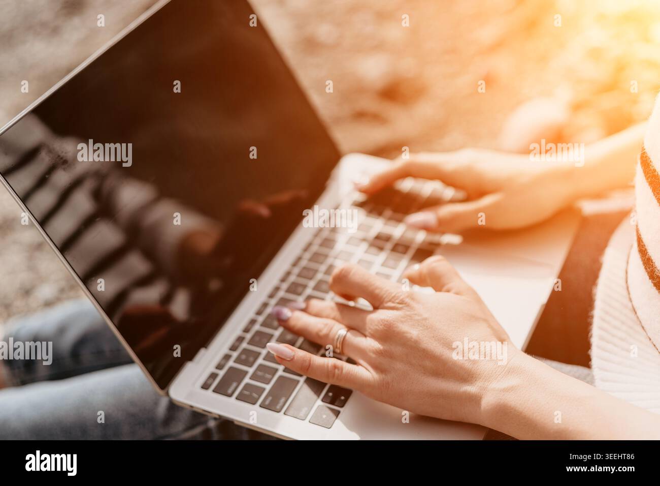 Typing laptop freelancer woman working on a silver computer outdoors representing a remote digital nomad lifestyle Stock Photo