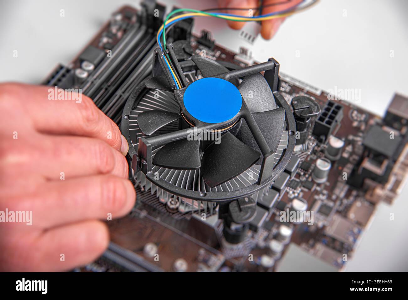 A person's hands installing a cooling fan onto a CPU socket. Stock Photo