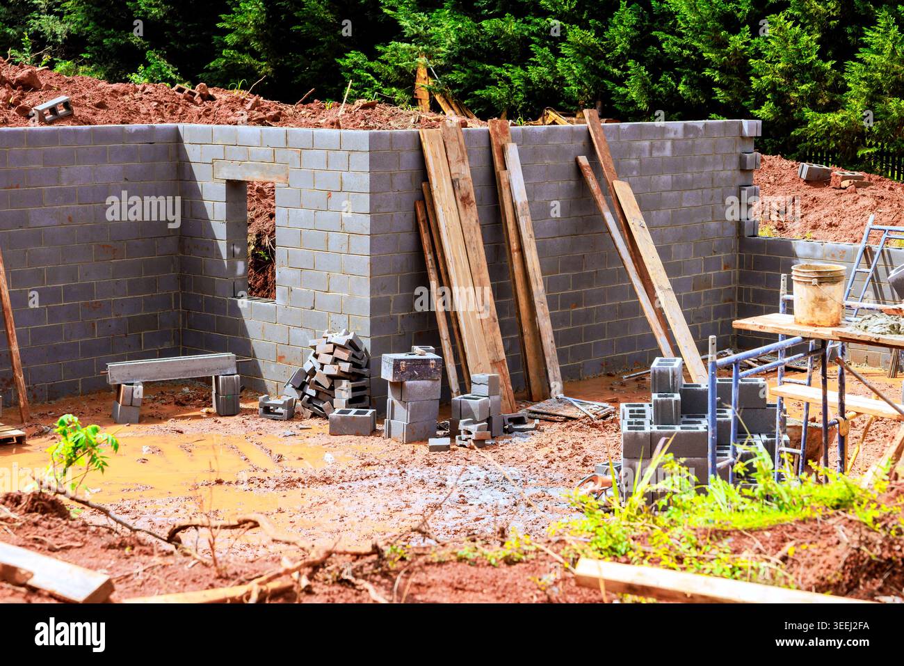 Workers are constructing brick wall at construction site with tools materials on ground around it. Stock Photo