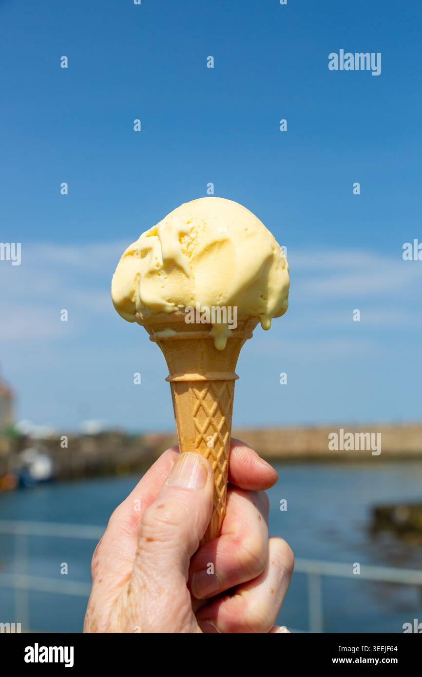 Close up of a melting vanilla ice cream in a traditional waffle cone Stock Photo