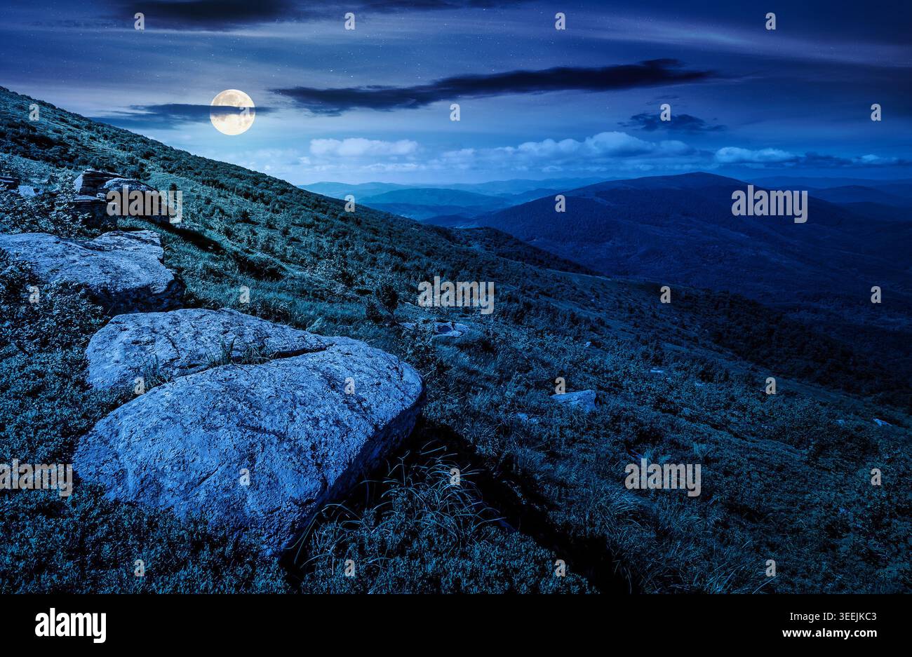 carpathian mountain summer landscape at night. full moon over alpine meadow with huge stones among the grass on top of the hillside near the peak of m Stock Photo