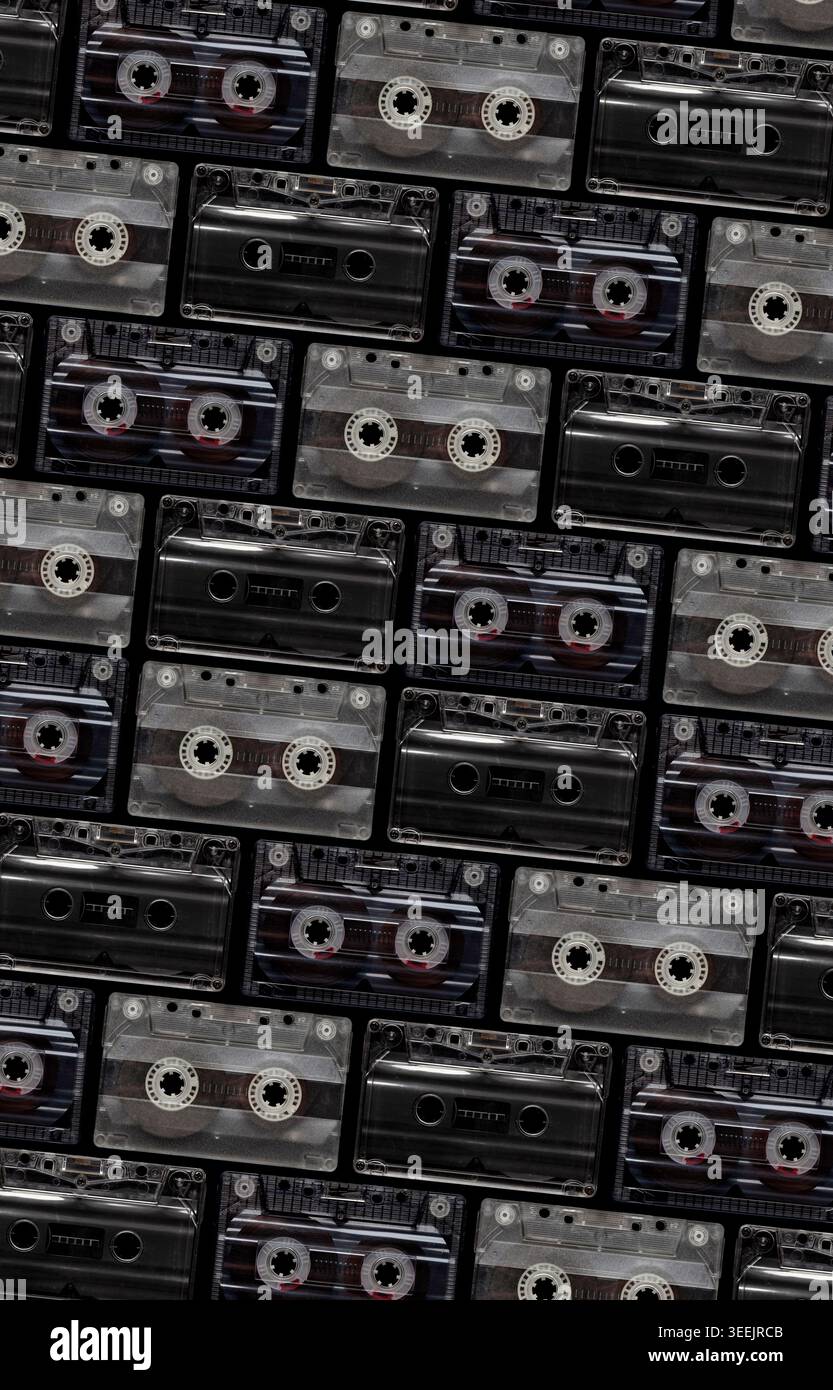 Pattern of vintage transparent and black audio cassettes arranged on a dark background. Stock Photo
