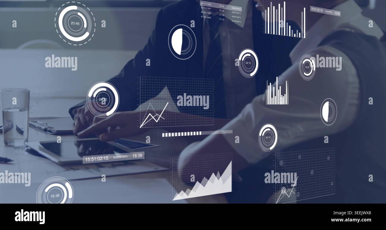Reviewing two colleagues in suits examining tablet and documents at meeting table, with AR charts Stock Photo