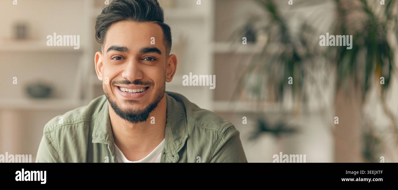 Young Man Smiles While Sitting Indoors With Plants in Background During Daytime Stock Photo