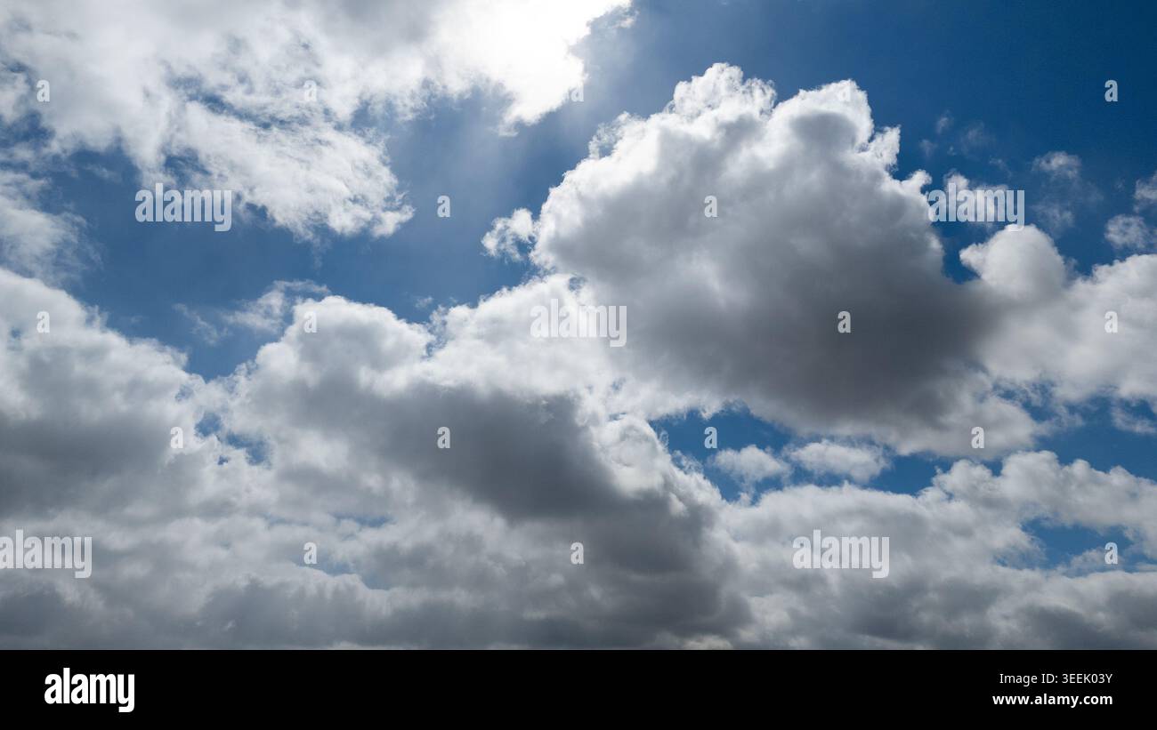 Bright sky with clouds while sun shining through white fluffy clouds in professi Stock Photo