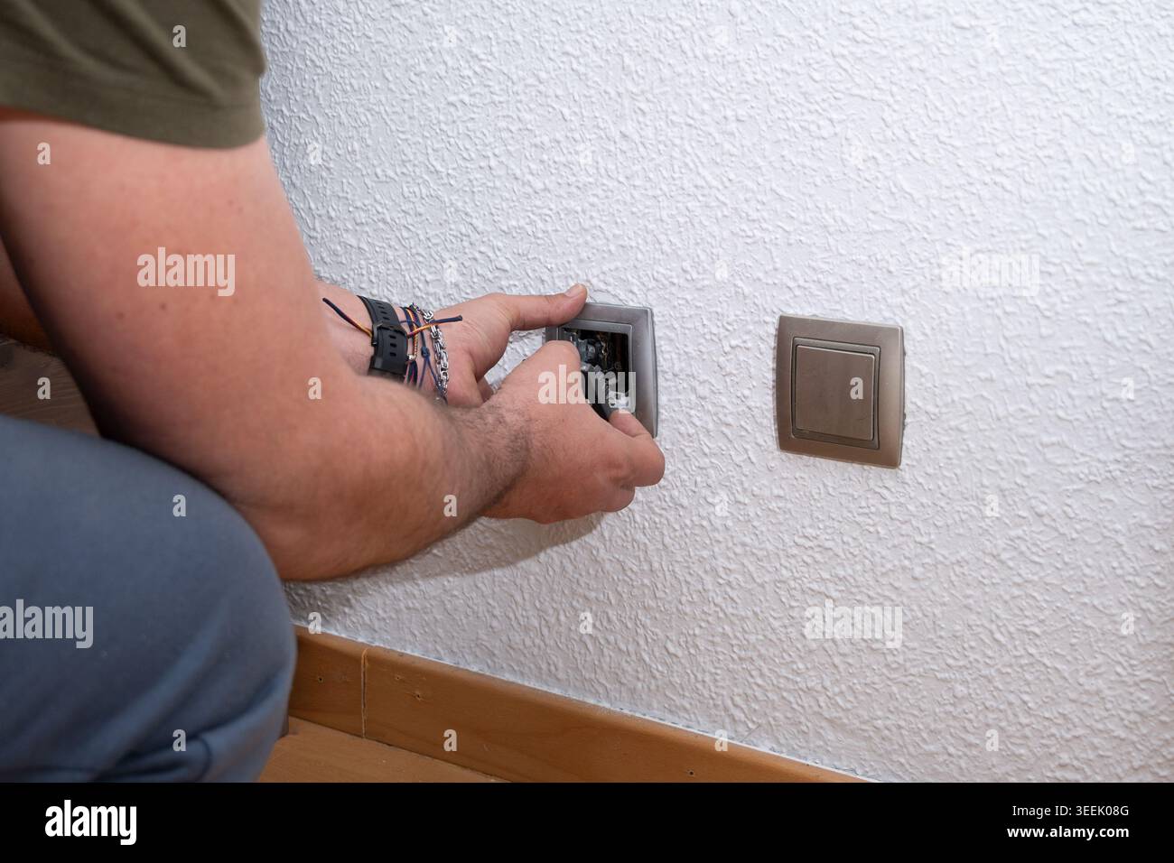 Man installing electrical light switch on white wall Stock Photo