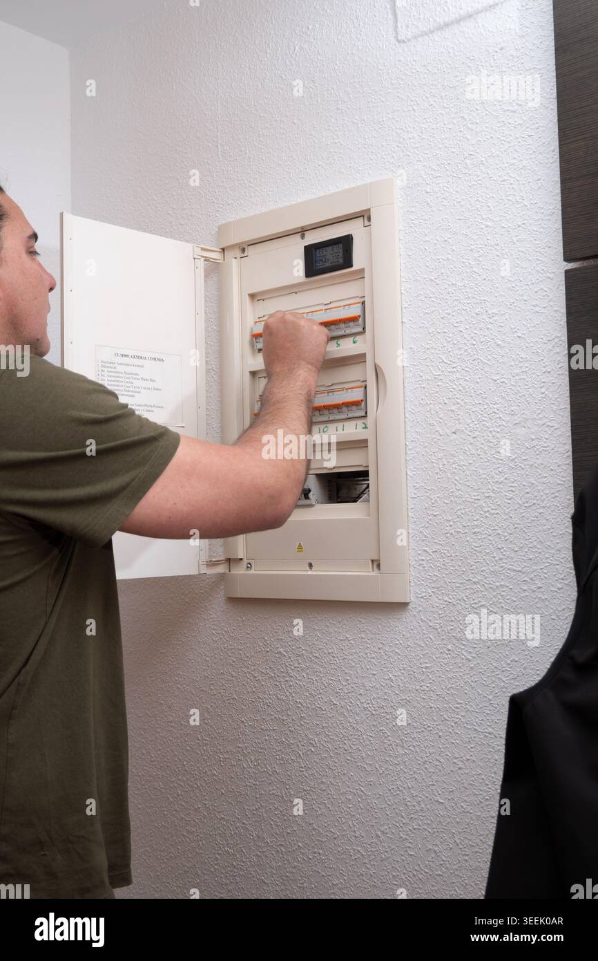 Man inspecting circuit breaker switch in home electrical panel Stock Photo
