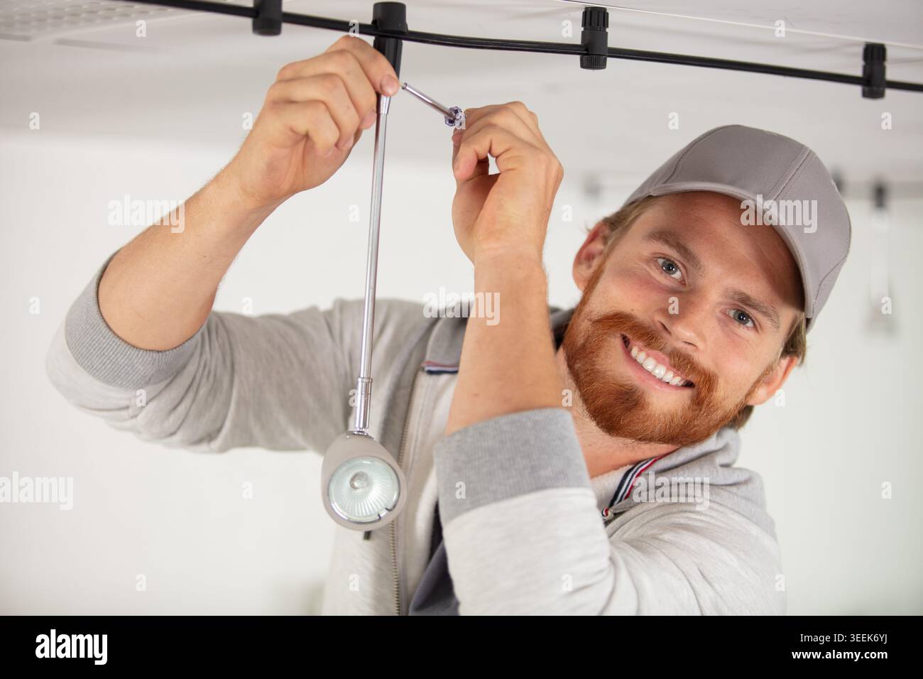 handsome young builder is twisting the light bulb in Stock Photo