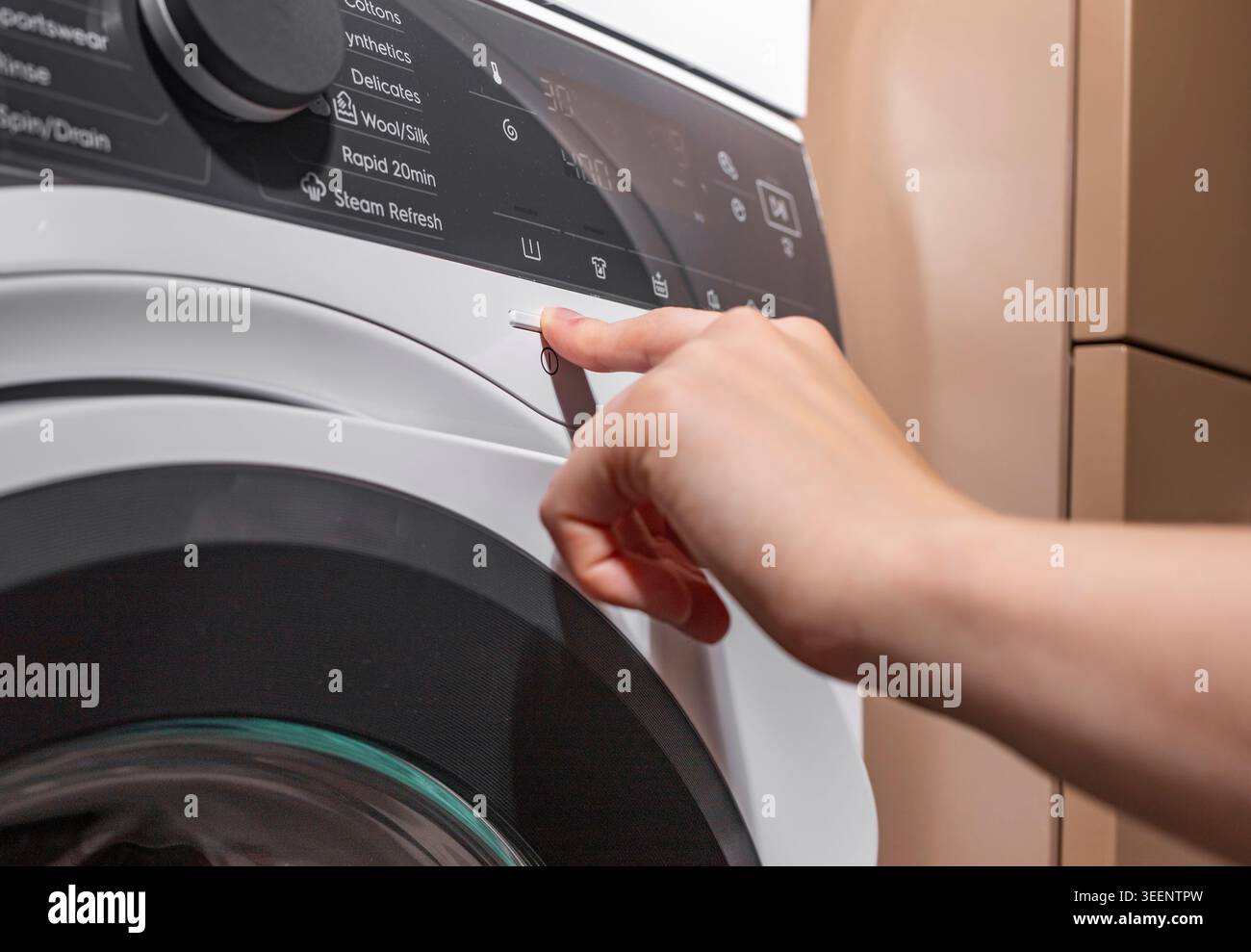 Hand turning on washing machine, launching laundry, pressing button with finger. Stock Photo