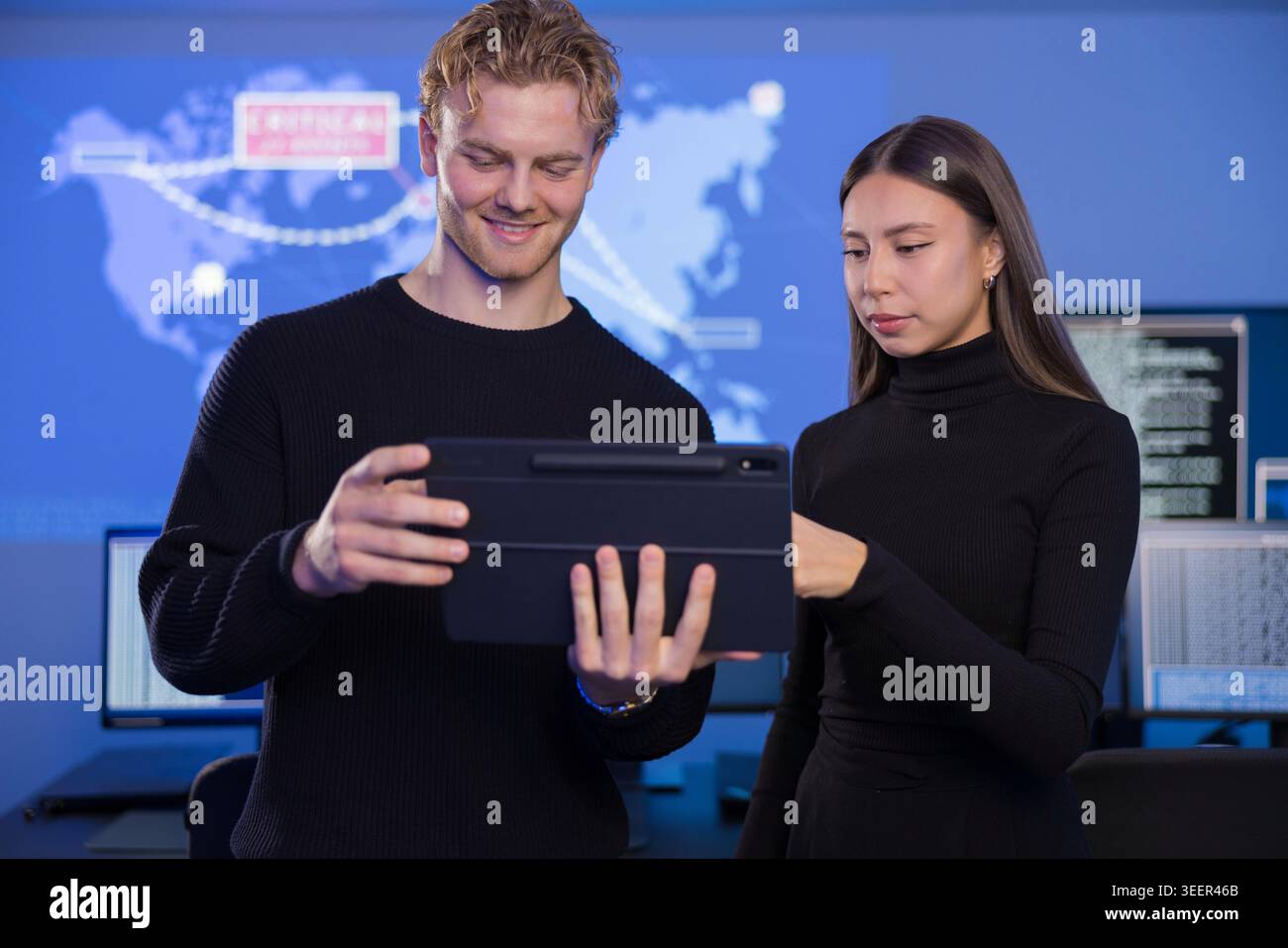 Two cybersecurity analysts collaborating in a modern SOC environment with digital maps Stock Photo