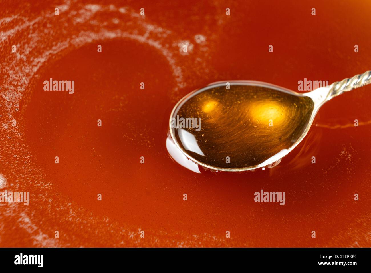 Spoon filled with golden maple syrup Stock Photo