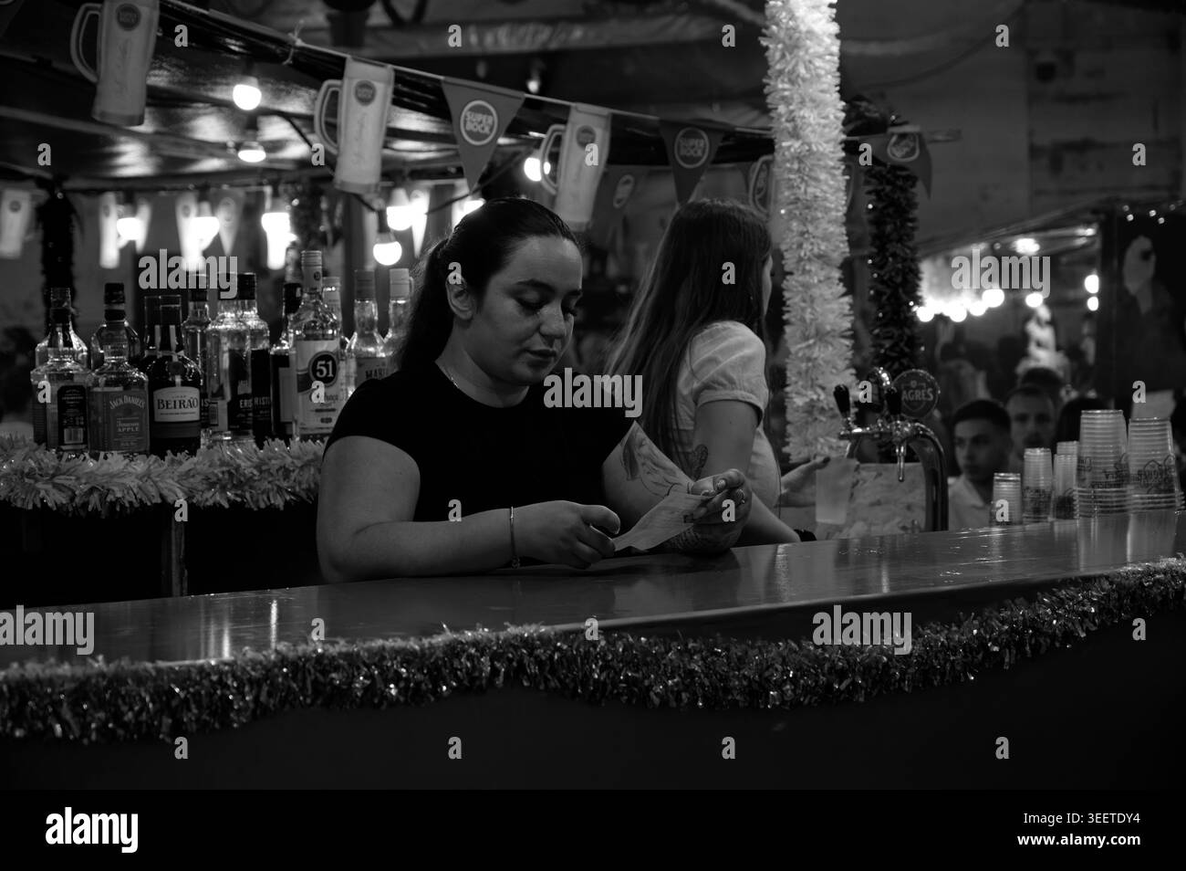 Bartender checks receipts at crowded Santos Populares festival bar in ...
