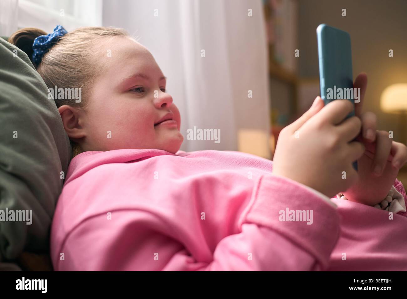 Girl with Down Syndrome Using Smartphone for Digital Communication Stock Photo