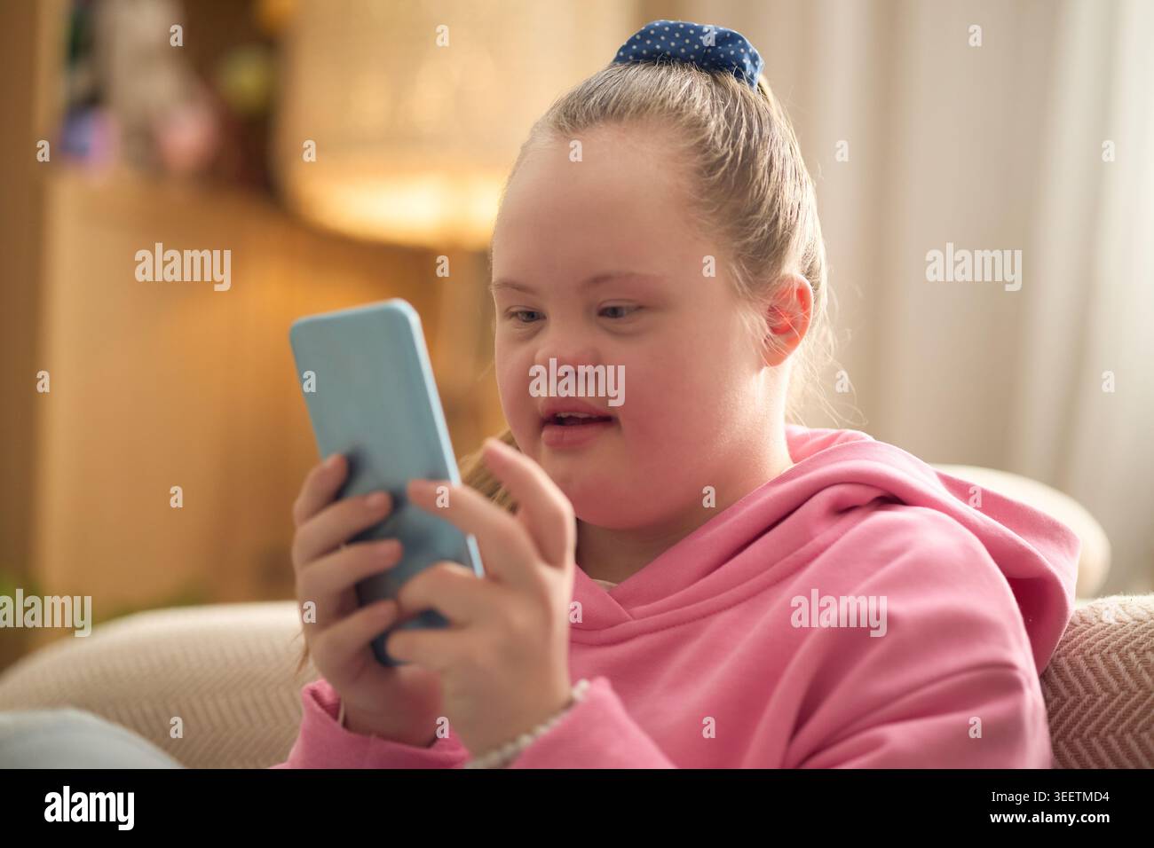 Girl with Down Syndrome Using Smartphone for Digital Communication Stock Photo