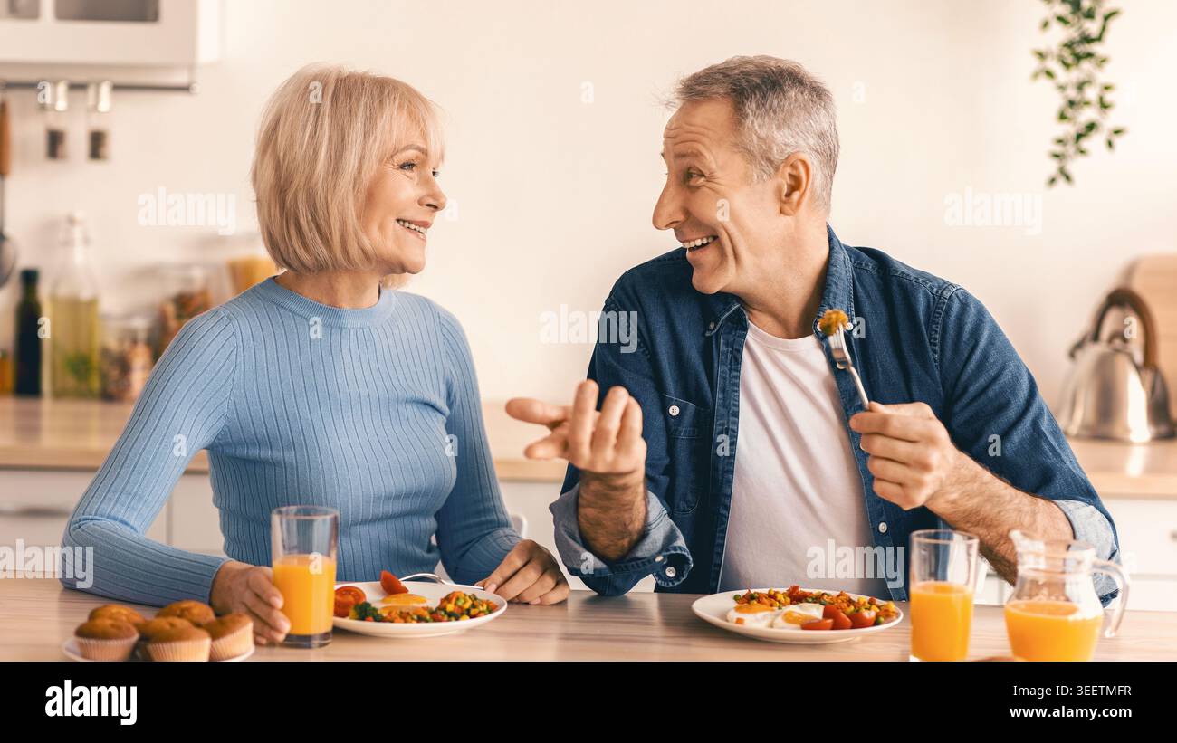 Couples Enjoy Breakfast Together in Bright Kitchen While Sharing Joyful Conversation Stock Photo