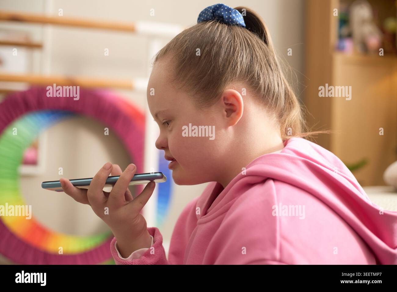 Girl with Down Syndrome Using Smartphone for Voice Communication Stock Photo