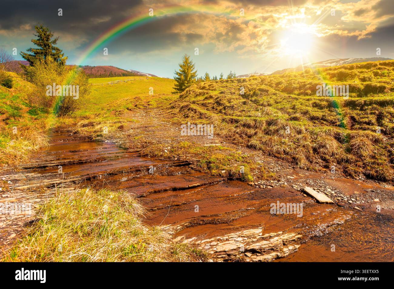 sunset over rural scenery in carpathian mountains. simple view of a countryside mountain landscape during springtime. brook near the grassy hills. wea Stock Photo