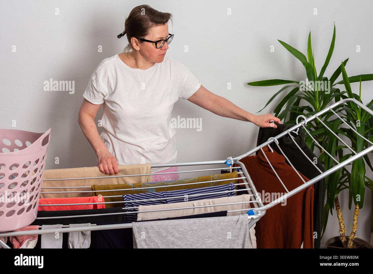She Has A Rack A 50-year-old woman with glasses hangs washed clothes on a drying rack ...