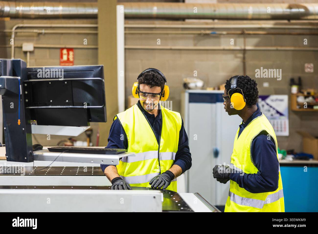Factory workers operating cnc machine in lumberyard Stock Photo