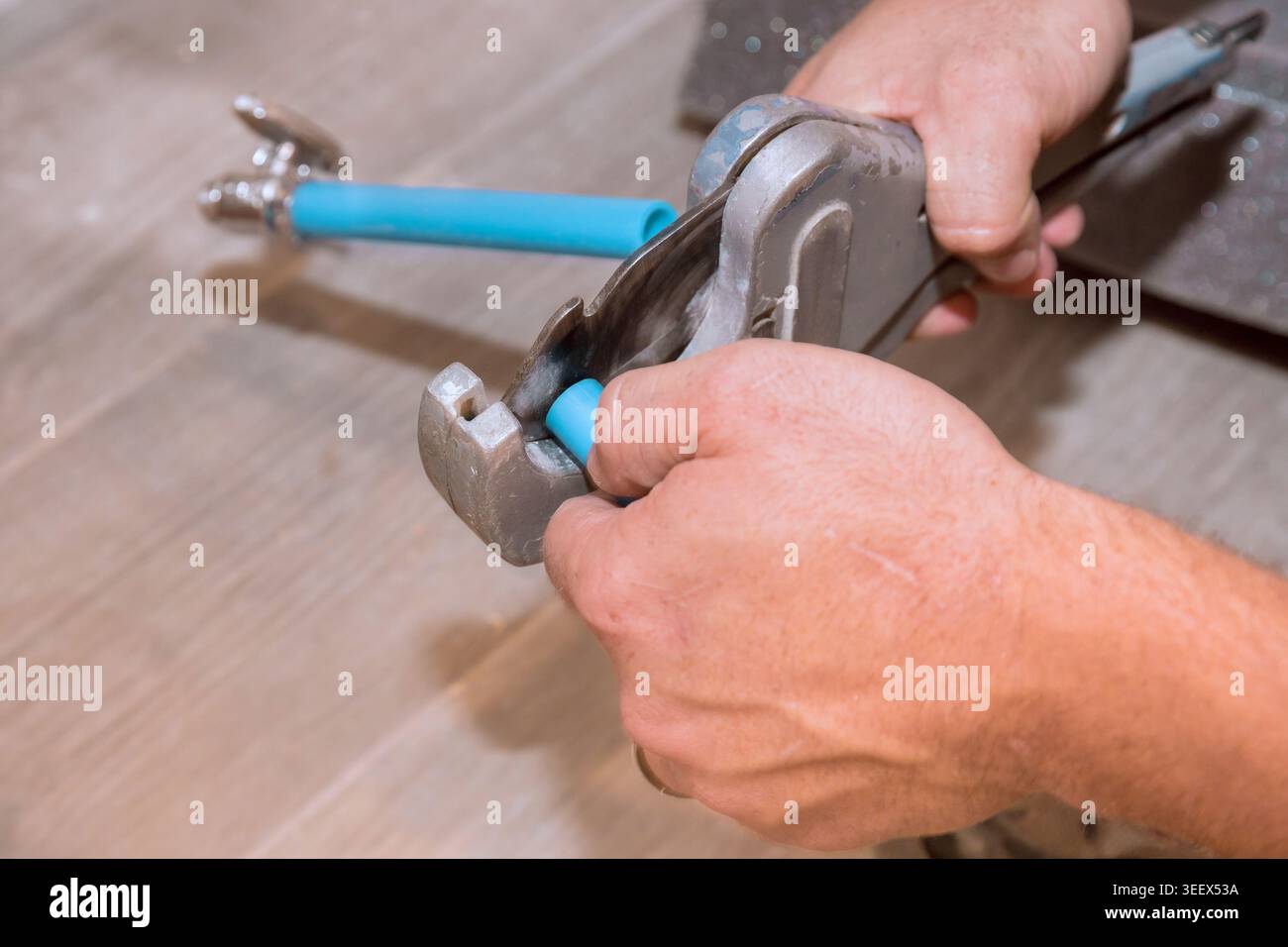Plumber works on blue pipe fitting using wrench while fixing plumbing in home Stock Photo