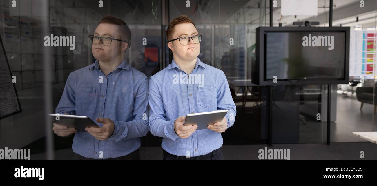 Professional man, corporate staff member with Down syndrome holding tablet Stock Photo