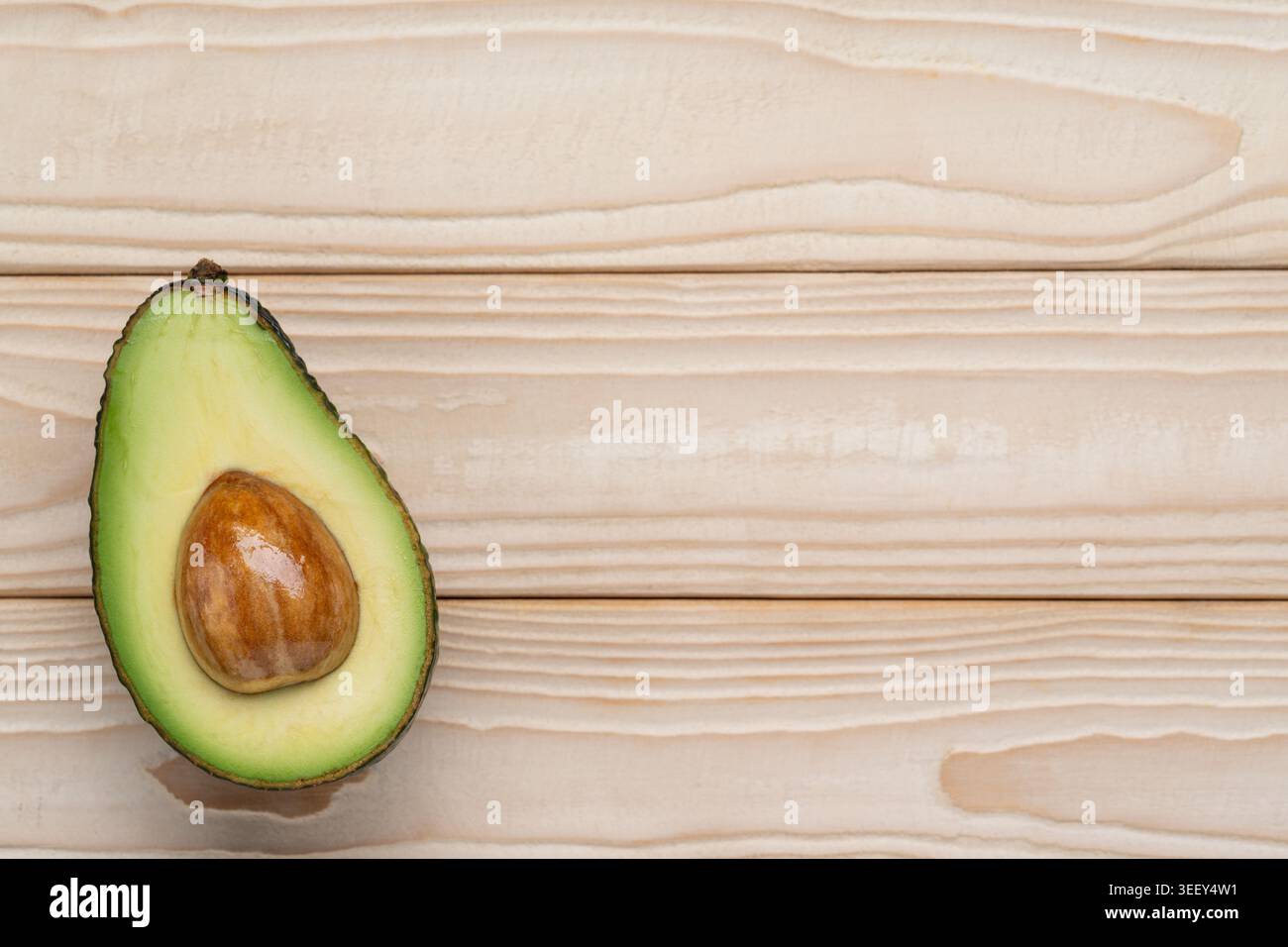 Avocado half on light wooden background with copy space Stock Photo