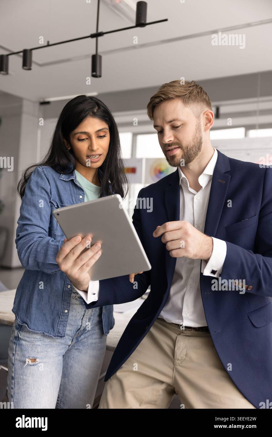 Two multiethnic male, female colleagues using tablet Stock Photo