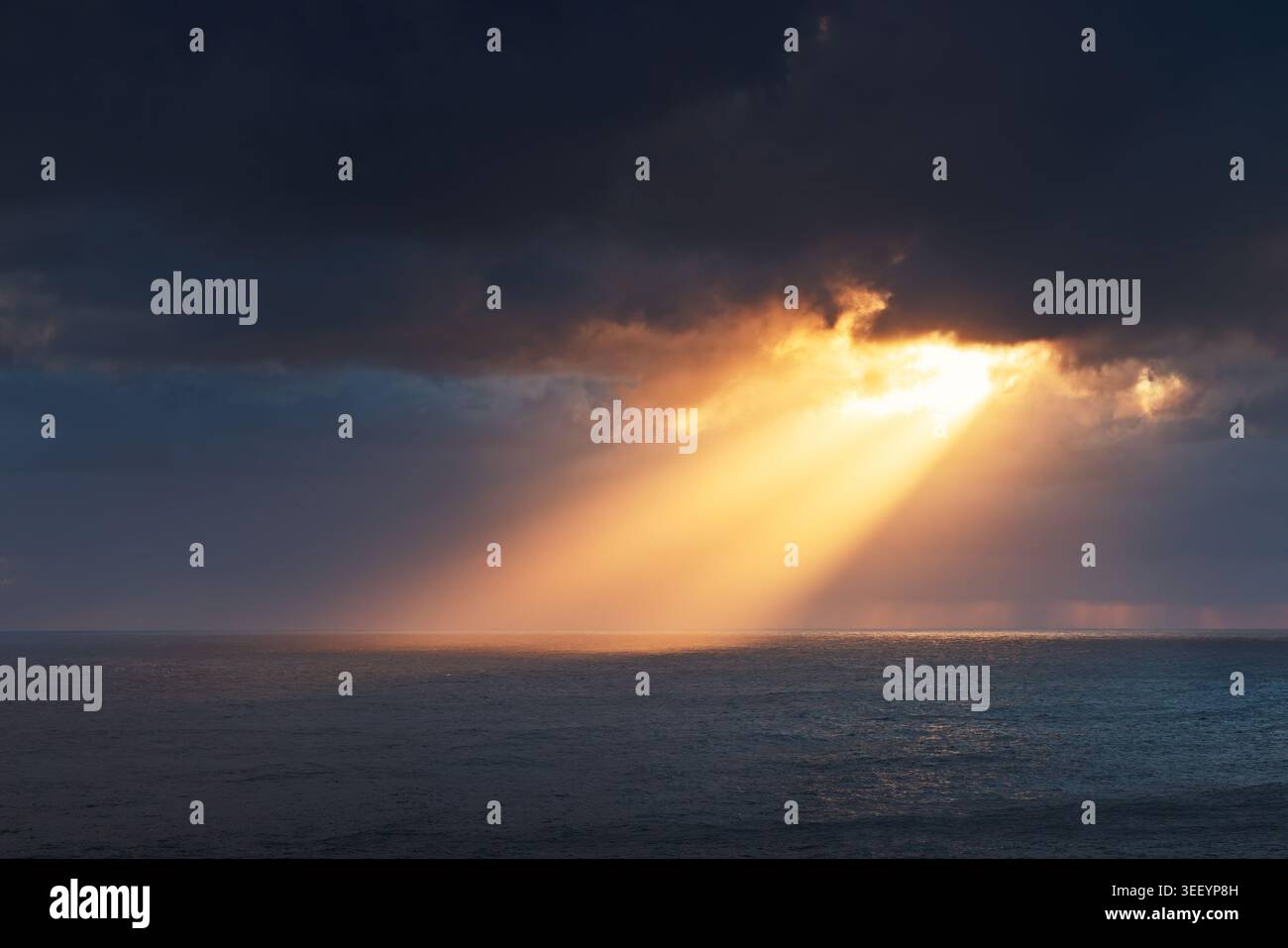 Dramatic Sun Rays over Sea Surface during Stormy Sunset Stock Photo