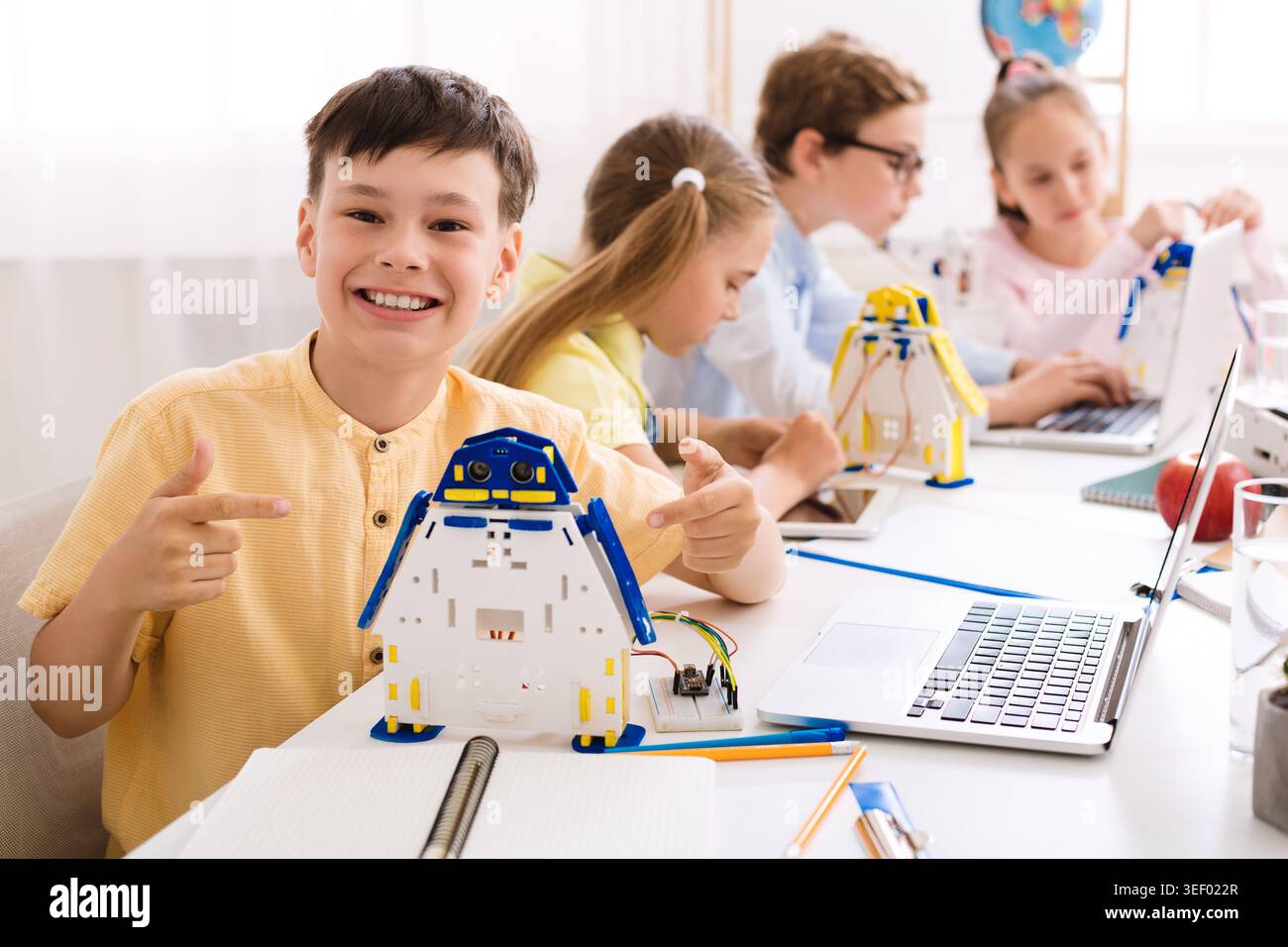 Children Engaged in Robotics Workshop Creating Penguin Models With Technology at School Stock Photo