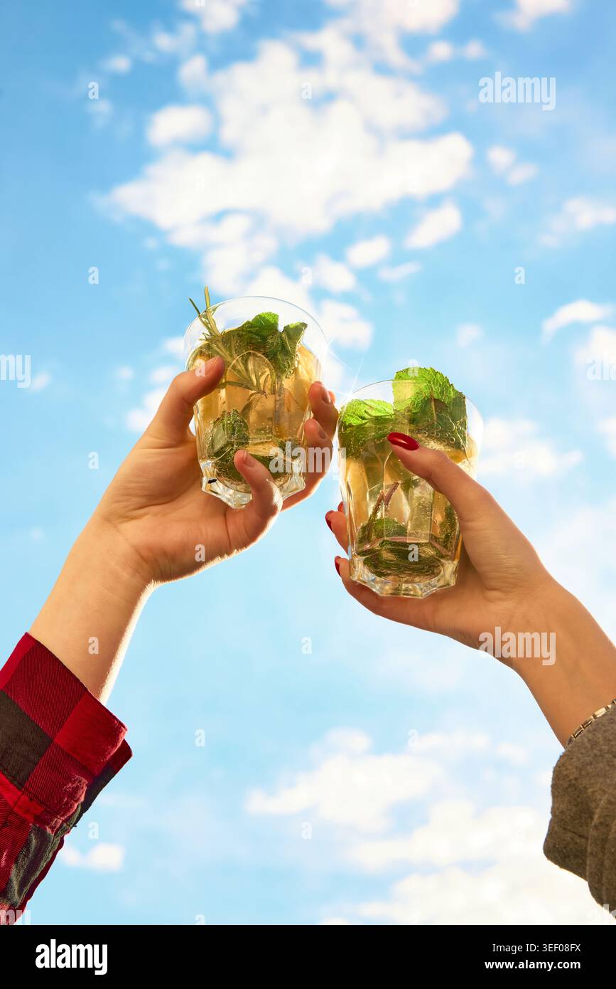 Friends clinking mint cocktails under bright summer sky Stock Photo