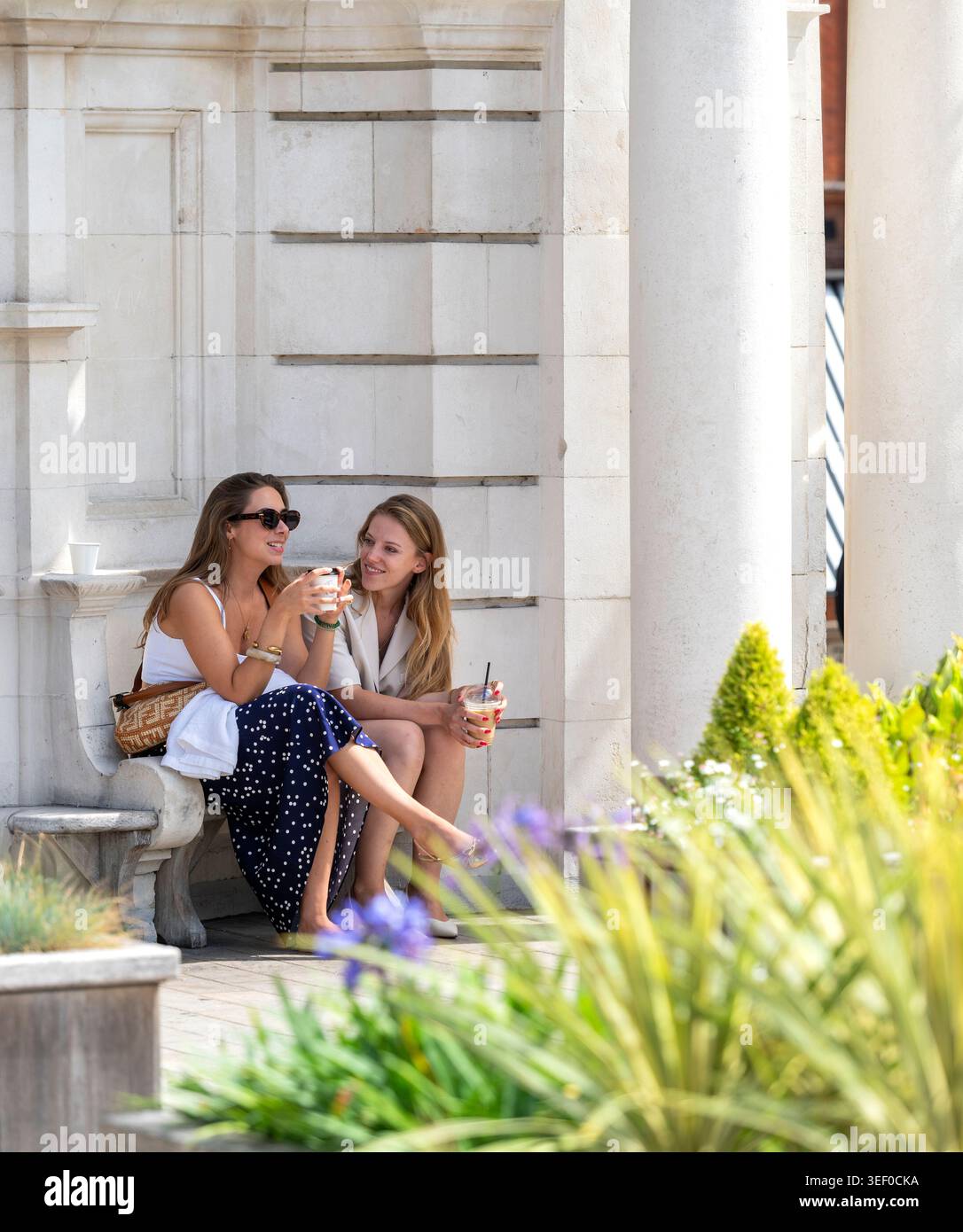 Two women sitting together outdoors in Mayfair, London during summer. Stock Photo