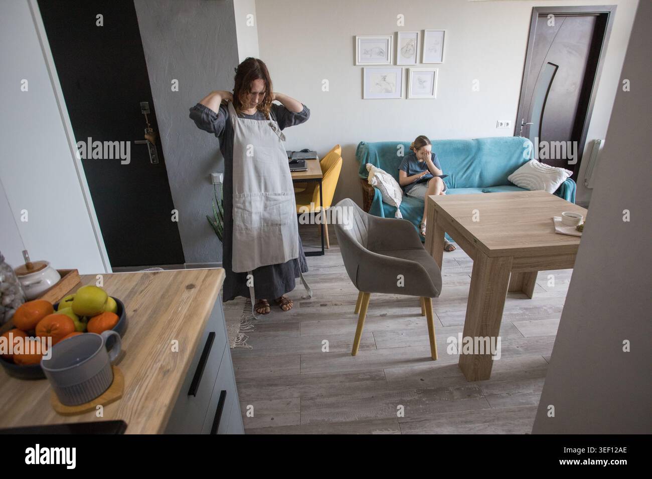 Mature mother setting the table while child learning and using pc tablet gadget at home Stock Photo