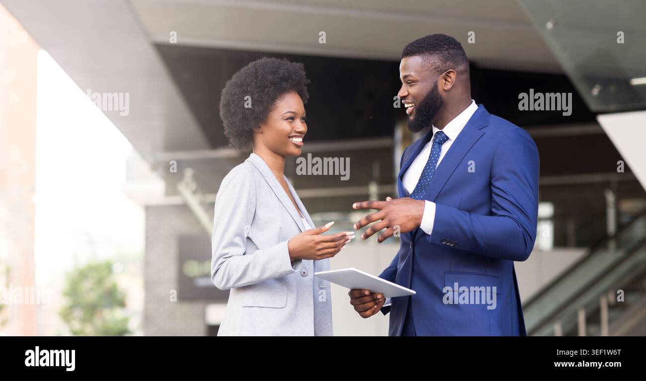 Two coworkers with digital tablet, discussing new project outdoors Stock Photo