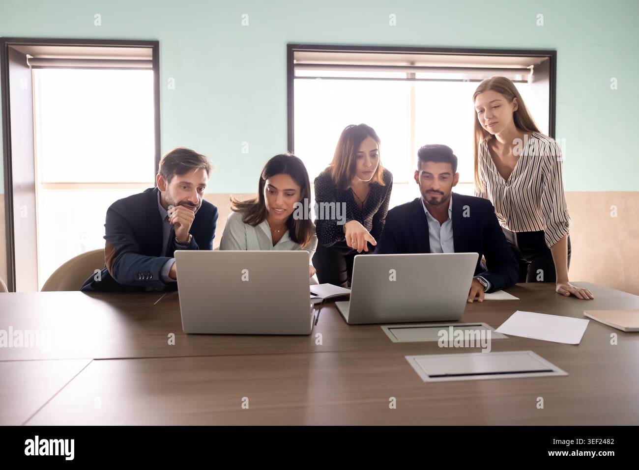 Focused diverse businesspeople collaborating on task using laptops Stock Photo