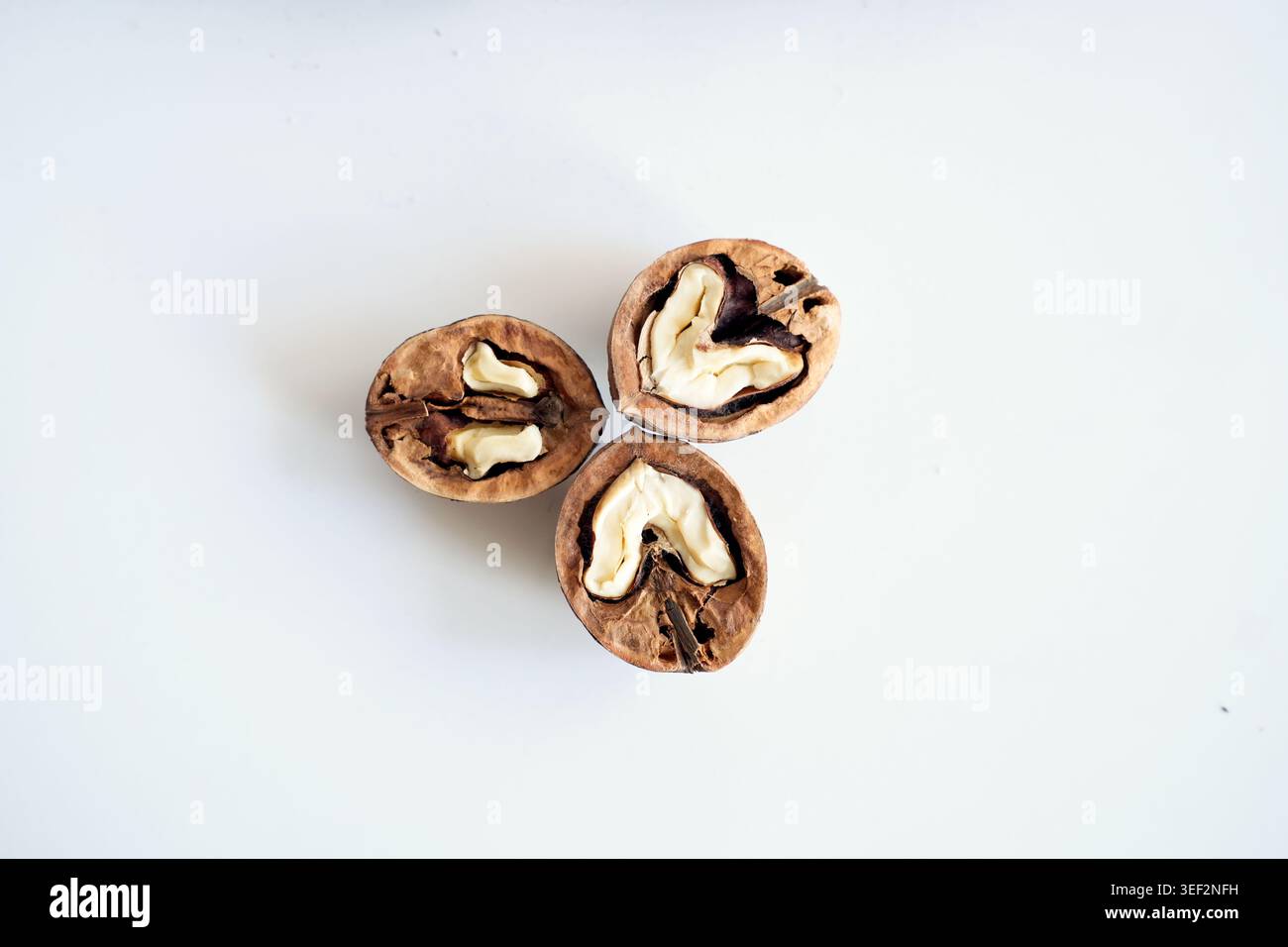 Cracked walnut halves with whole nuts on white background. Stock Photo
