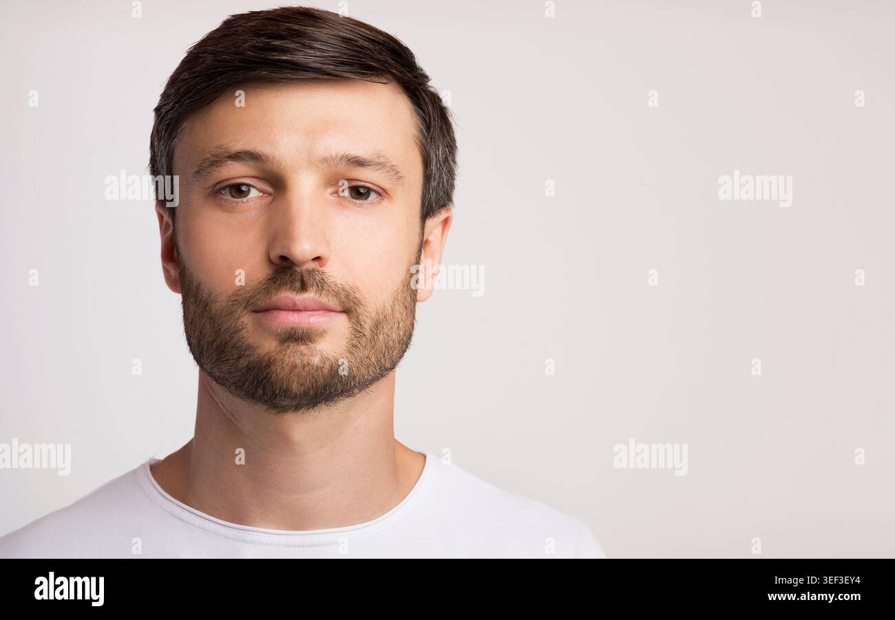 Young Man With Beard and Short Hair Poses Against a Plain Background Stock Photo