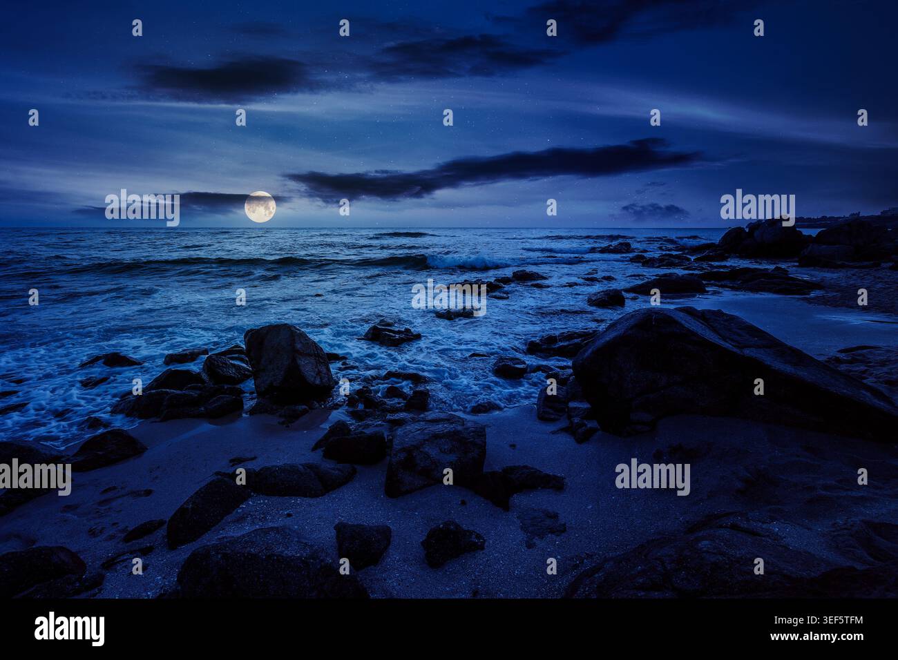 huge stones on a sandy beach at night. wonderful summer vacation season at the black sea. full moon over calm waves washing the sand shore. mysterious Stock Photo