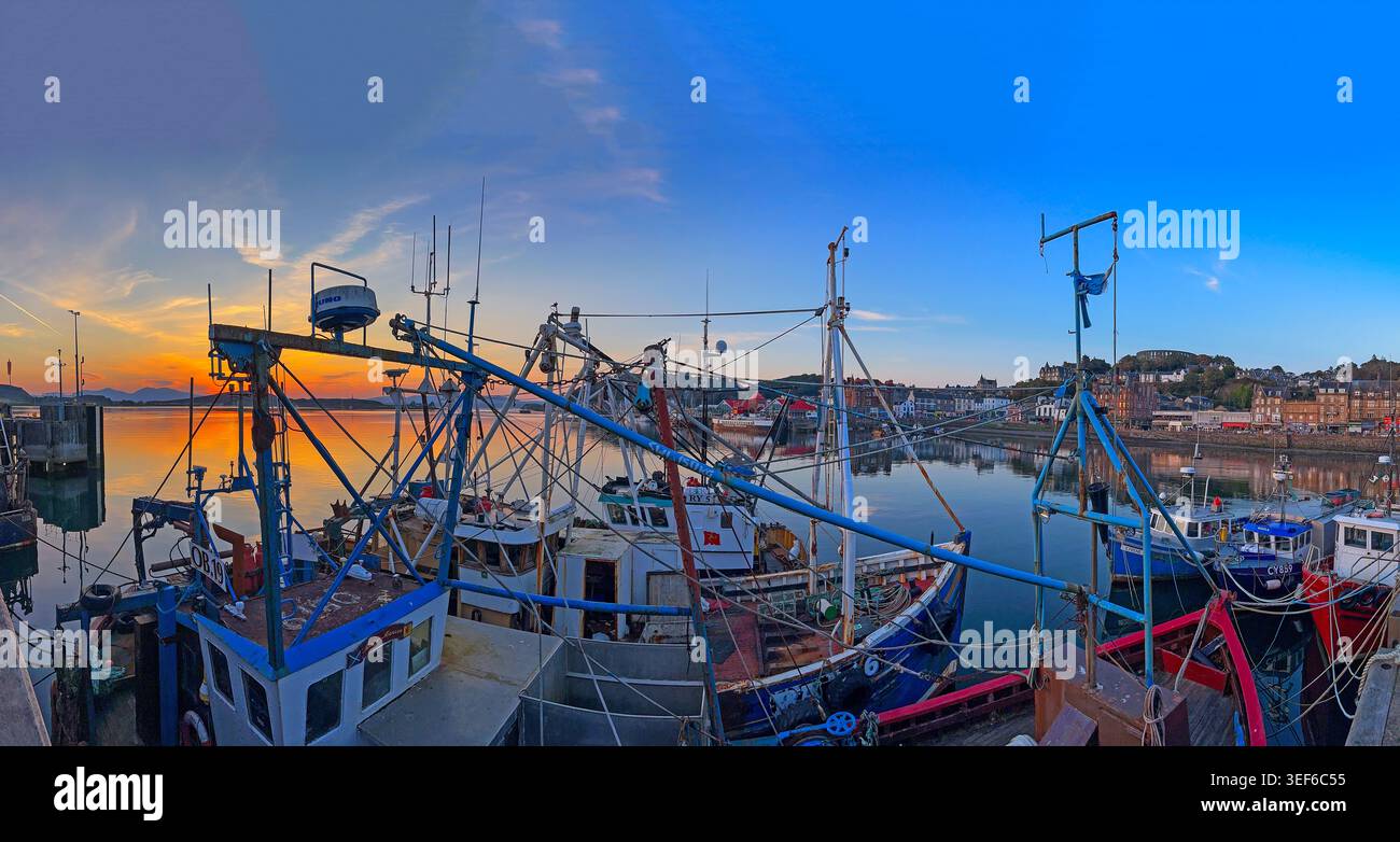 Oban Harbour at dusk with fishing boats and trawlers under a vivid sunset, Argyll and Bute, Scotland, UK Stock Photo