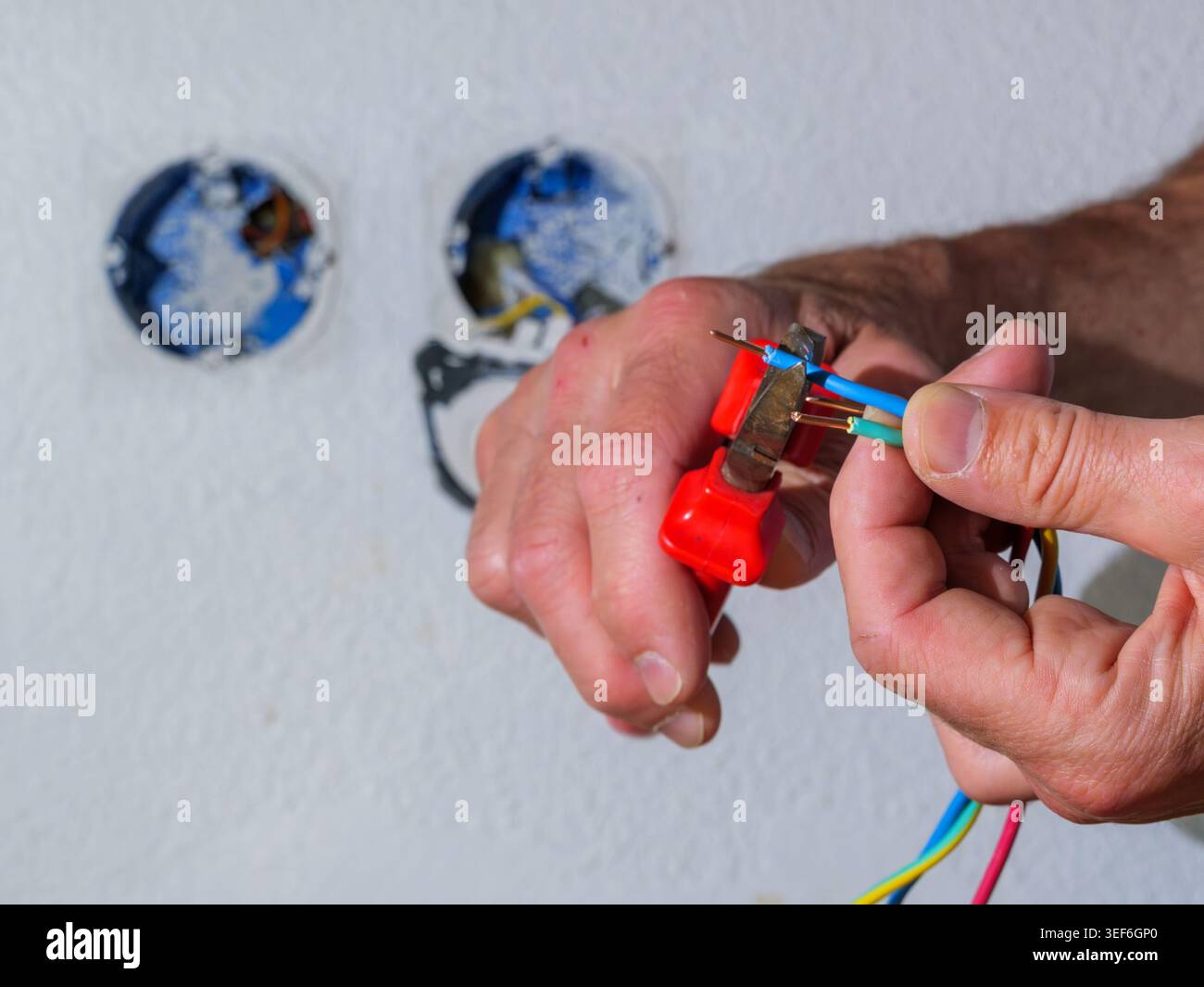 Cutting electrical wires during home installation work. Close-up of hands using tool while working with electrical cables. Stock Photo