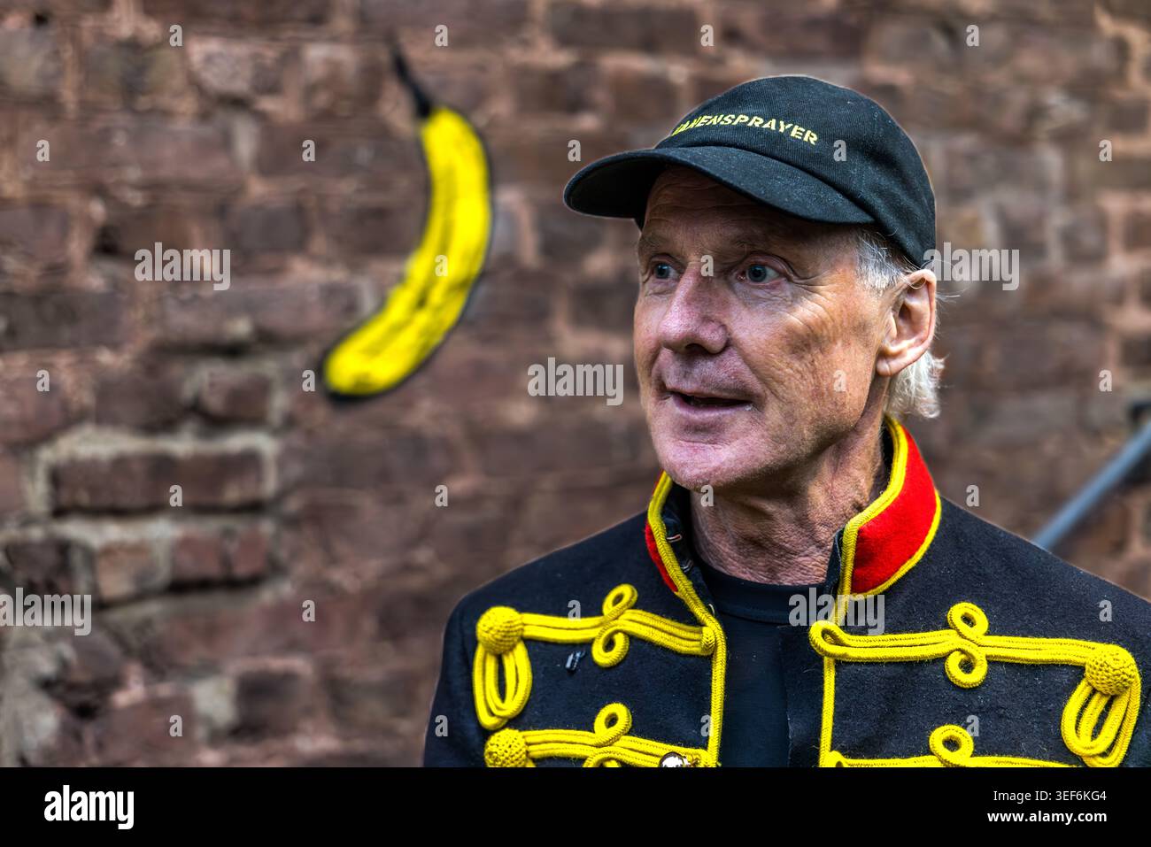 Thomas Baumgärtel at the opening of the exhibition “40 Years of Bananensprayer”. This major project runs from May to the end of September 2026 and is themed “Freedom for Art”. The NiederrheinTour 2026 will showcase 40 groups of works spanning 40 years at 40 art venues. Here, in front of the Grevenbroich dispatch hall, freshly adorned with a spray-painted banana, are images from the “Banana Pointillism” series. Grevenbroich, Nordrhein-Westfalen, Deutschland Stock Photo