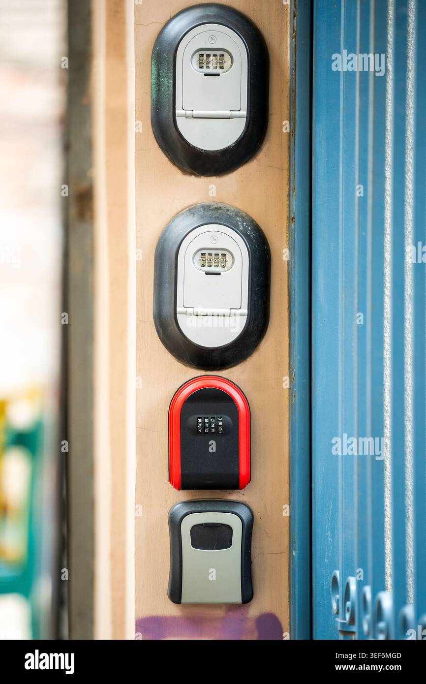 Various lock boxes with keys code inside located on wall near entrance gate at apartment building. Stock Photo